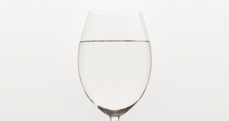 poured water into wine glass over white background