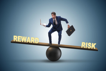 Businessman balancing between reward and risk business concept