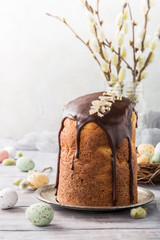 Fototapeta na wymiar Easter orthodox sweet bread, kulich with chocolate glaze and quail eggs on light background. Easter holidays breakfast concept with copy space.