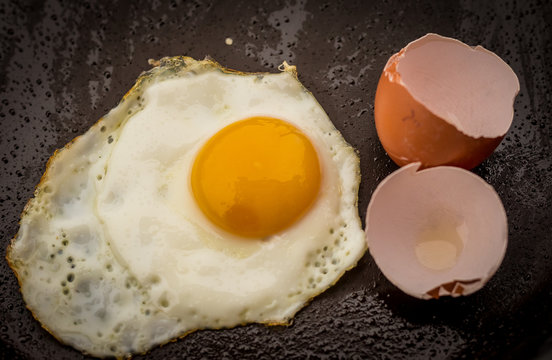 скорлупа и куриное яйцо на сковороде