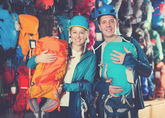 Obraz na płótnie Canvas Glad couple in shop chooses backpacks