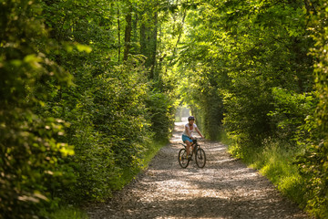 Naklejka premium Woman rides bicycle in the beautiful green forest