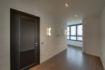 The room with a white brick wall, lamps and a dark wooden door