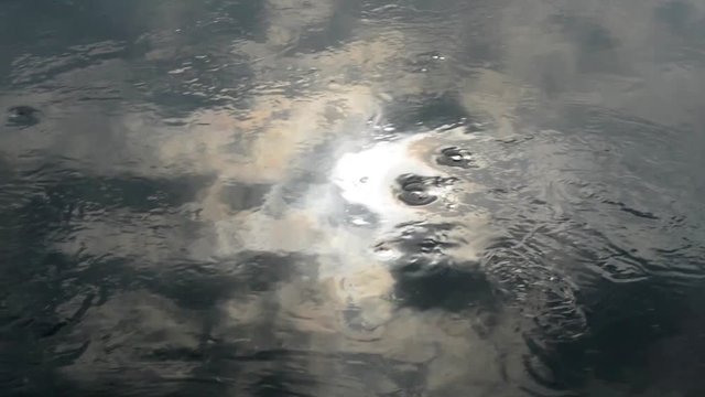 Riflessi di luce prodotti dal sole sull'acqua del fiume spinta dalla corrente