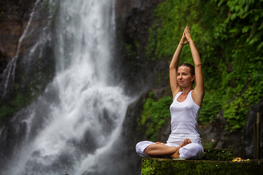 Woman practices yoga at Gitgit waterfall on Bali in indonesia