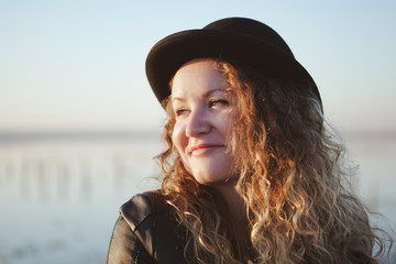 Graceful young woman with long shiny hair gladly posing while walk outside in good mood. Outdoor close-up photo of pleased girl in trendy autumn hat.