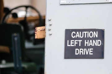 Sign on the back of an old Landrover warning following motorists that it is left-hand drive.