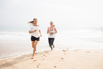 two women is jogging the seashore on an overcast day