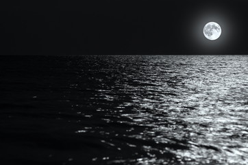 moonlight on the waves at night in the sea on long exposures. black and white photo.