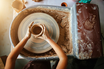 Female potter working at throwing wheel at studio. Clay workshop