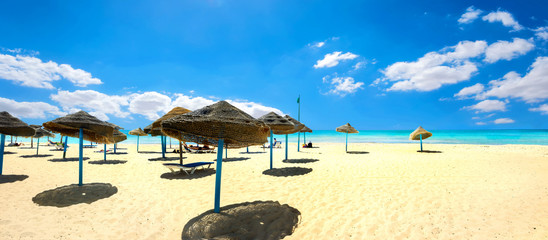 Sunshades on the sandy beach at sunny day. Nabeul, Tunisia, North Africa