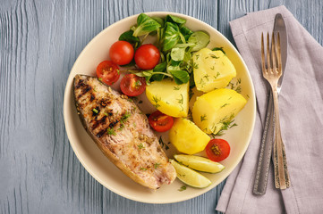 Grilled fish served with vegetables (potatoes and tomatoes).
