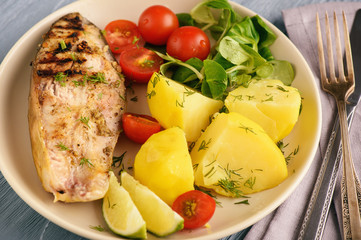 Grilled fish served with vegetables (potatoes and tomatoes).