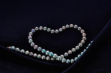 necklace of black pearl in the form of a heart on dark blue velvet