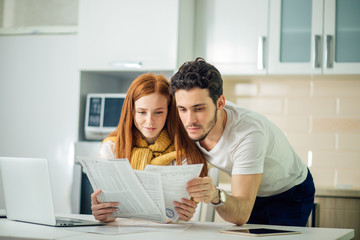 cheerful young couple calculating their bills at home