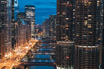 Fototapeta premium Chicago, Illinois. Cityscape at night with marina city tower, river, empty road and bridge in sight. Taken from London House Chicago. July, 2017.