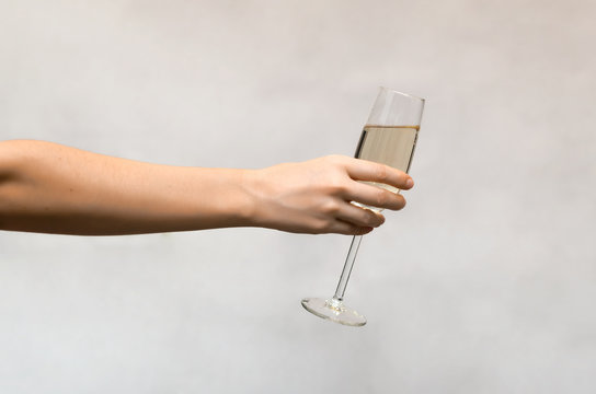 Female Hand Holding A Glass Of Champagne Isolated On White Background.