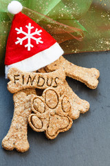Mit selbstgebackenen Keksen gefüllte Weihnachtsmütze auf Schiefertafel von oben
