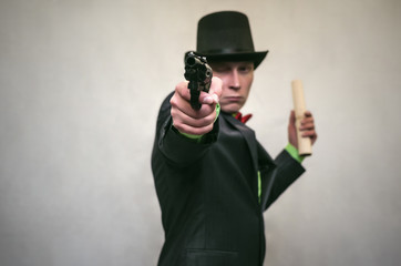 The spy. Secret service. Detecive agent holds pistol gun in his hands and secret documents with compromising evidence and is examined studying the situation. Retro gangster isolated.