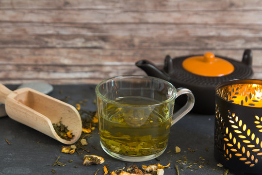 hot green tea in cup composition with candle and tea pot