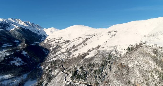 Vue a&eacute;rienne au dessus d'une route dans les montagnes rocheuses enneig&eacute;es - neige pic chaine de montagne ciel bleu voyage vacance arbre route voiture chemin 