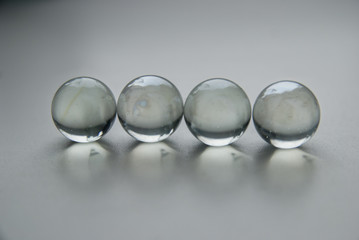 Four crystal glass balls in line on white grey background surface.