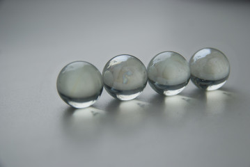 Four crystal glass balls in line on white grey background surface.