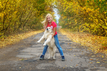 Fototapeta premium Young girl playing with dog golden retriver on the road in yellow forest. friendship with pets