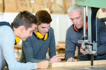 carpenter with apprentices in workshop