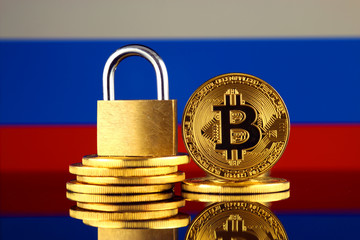 Physical version of Bitcoin, golden padlock and Russia Flag. Prohibition of cryptocurrencies, regulations, restrictions or security, protection, privacy.