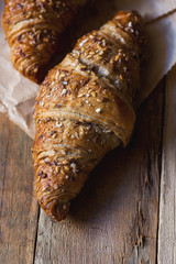 Fresh Home Baked Wholemeal Rye Croissants with Sesame Seeds on Craft Paper Weathered Wood Table Soft Natural Light Breakfast French Pastry Copy Space