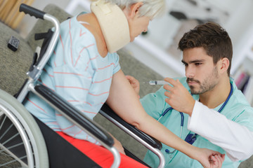 Obraz premium Medic giving injection to patient in wheelchair