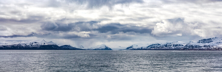Panorama of clouds over snowy mountains in the arctic
