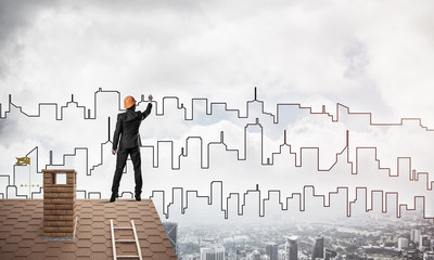 Man architect draw silhouette of modern city on blue sky. Mixed 