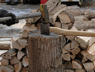 Hitting ax with a sledge hammer to split firewood