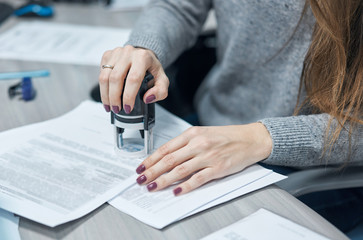 girl puts a stamp on documents in the office