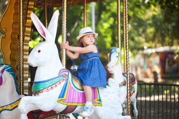 Toddler kid riding vintage roundabout carousel.