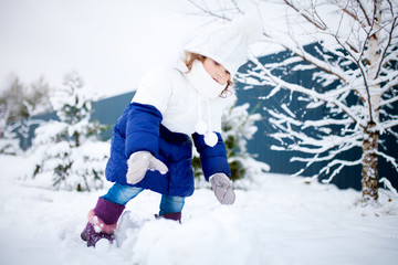 Fototapeta na wymiar Little girl playing snowballs, winter activity.
