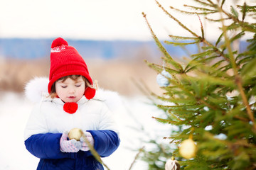 Little girl decorating Christmas three outdoors.