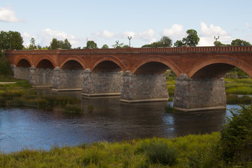 Fototapeta premium old Brick bridge across the River Venta in the city of Kuldiga Latvia