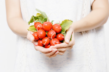 The girl holds a radish in her hands. A young woman with a radish.