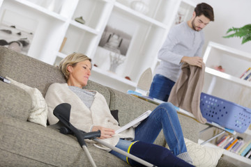 mature wounded woman resting on sofa with carer