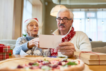 Portrait  of loving senior couple looking at family photographs during Christmas dinner in cafe