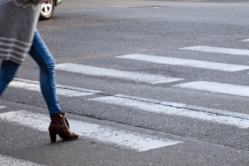 Woman crosses the road on the pedestrian crossing. Motion blur.