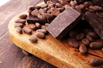 Dark chocolate pieces, stacks and cocoa beans, culinary background.