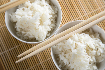 Zwei Schalen Basmati Reis mit Stäbchen auf Matte
