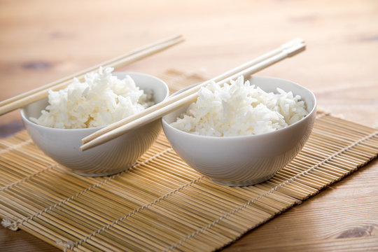 Zwei Schalen Basmati Reis mit Stäbchen auf Matte