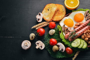 English breakfast. Fried eggs, sausages, bacon, beans, toasts, tomatoes, coffee cup on stone table. Top view with space for your text