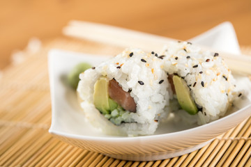 Zwei Inside Out Sushi mit Lachs und Avocado an Holz Stäbchen