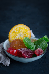 Fruit crystallized in a bowl on a dark background. Vertical.